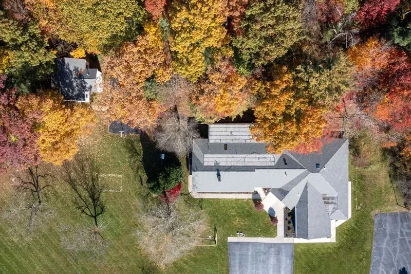 The image depicts a two-story house surrounded by autumn foliage.